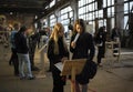Two girls looking at the artifact in the exhibition organized in the production hall of an old plant, people walking on a