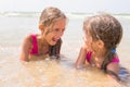 Two girls lying in shallow water and have fun looking at each other Royalty Free Stock Photo