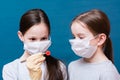 Two girls in medical masks are examining a coronavirus which one of them holds in tweezers. Hand in latex glove.