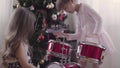 Two girls near christmas tree playing drum kit Royalty Free Stock Photo