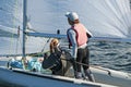 Two girls one standing other sitting sailing a racing skiff closeup