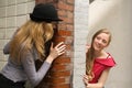 Two girls peeking around the wall Royalty Free Stock Photo