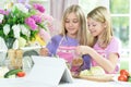 Two girls in pink aprons preparing fresh salad