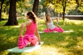 Two girls practice yoga in the park in the Crooked Monkey pose.