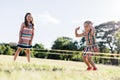 Two girls playing Chinese jumping rope in the park.