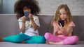 Two girls playing games on smartphones instead playing together gadget addiction