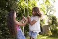 Two Girls Playing Together On Tire Swing In Garden Royalty Free Stock Photo