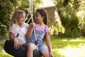 Two Girls Playing Together On Tire Swing In Garden Royalty Free Stock Photo