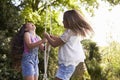 Two Girls Playing Together On Tire Swing In Garden Royalty Free Stock Photo