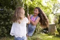 Two Girls Playing Together On Tire Swing In Garden Royalty Free Stock Photo