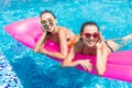 Two girls playing with water in the pool on inflatable pink mattresses Royalty Free Stock Photo