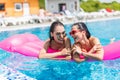 Two girls playing with water in the pool on inflatable pink mattresses Royalty Free Stock Photo