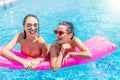 Two girls playing with water in the pool on inflatable pink mattresses Royalty Free Stock Photo