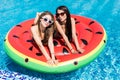 Two sexy young girls playing with water in the pool mattresses watermelon Royalty Free Stock Photo