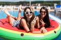 Two sexy young girls playing with water in the pool mattresses watermelon Royalty Free Stock Photo