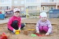 Two girls plays in sandbox on children playground