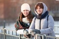 Two girls portrait dressed winter clothes, Caucasian females looking at camera and smiling, cold sunny weather