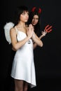 Two girls posing in costumes of angel and demon Royalty Free Stock Photo