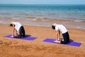 Girls practicing camel yoga pose on the beach