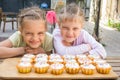 Two girls pretending funny faces, sitting in front of cupcakes Royalty Free Stock Photo