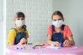 Two girls in protective medical masks play board games at home