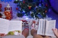 Two girls read books in the new year on the background of a Christmas tree with gifts Royalty Free Stock Photo