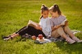 Two girls reading books sitting on green grass in nature. Friends enjoying time together in summer park Royalty Free Stock Photo