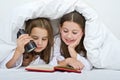 Two girls reading under blanket Royalty Free Stock Photo