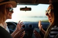 Happy excited young women driving in car and making high five gesture on summer vacation trip. Two girls rejoice they Royalty Free Stock Photo