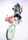 Two girls riding a bike making funny faces - on bluish background