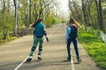 Two girls on roller skates ride along the road next to each other