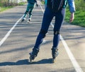 Two girls on roller skates ride along the road next to each other Royalty Free Stock Photo