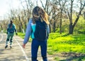 Two girls on roller skates ride along the road next to each other