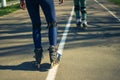 Two girls on roller skates ride along the road next to each other Royalty Free Stock Photo