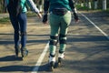 Two girls on roller skates ride along the road next to each other Royalty Free Stock Photo
