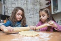 Two girls rolling out dough on kitchen table Royalty Free Stock Photo