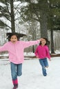 Two girls running through the snow Royalty Free Stock Photo