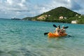 Two girls sailing in yellow kayak next to a tropical exotic island.