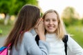 Two girls schoolgirl girlfriends, summer in city on nature. He speaks in his ear. The concept, mystery, surprise, truth Royalty Free Stock Photo