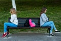 Two girls schoolgirl quarreled in the summer in park. They sit on a bench. The concept of conflict, scandal, problems in