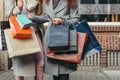 Two girls with shopping bags in front of show-window with sale written on it Royalty Free Stock Photo