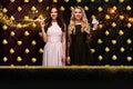 Two girls are showing two aces and chips, smiling, posing against colorful sparkling background with golden card suits Royalty Free Stock Photo