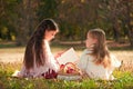 Two girls sisters read the book on the grass Royalty Free Stock Photo