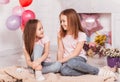 Two girls sisters in a room decorated with balloons look at each other. Friendship Royalty Free Stock Photo