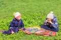 Two little sisters are sitting on the green fresh grass in a clearing and communicate with each other. Royalty Free Stock Photo