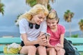 Two girls sisters, teenage and preteen look at a smartphone