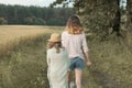 Two girls sisters walking together on country road back view Royalty Free Stock Photo