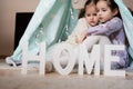 Two girls sisters at wigwam tent with wooden home letters