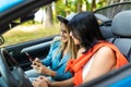 Two women sit in car in front seats and use phones in convertible car Royalty Free Stock Photo