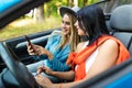 Two women sit in car in front seats and use phones in convertible car Royalty Free Stock Photo